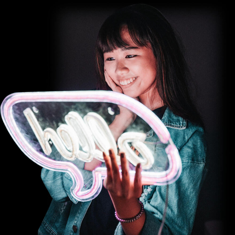 Person holding a pink hello LED neon sign
