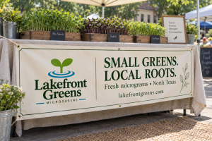 Cream Lakefront Greens banner with green branding and Small Greens Local Roots wording at a produce display.