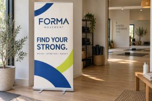 Freestanding Forma fitness banner with blue branding and Find Your Strong wording in a bright interior.