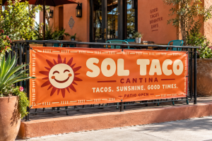 Orange Sol Taco Cantina banner with a sun logo displayed along an outdoor restaurant patio.